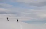 Two ski tourers climbing a wide untracked slope above Courchevel