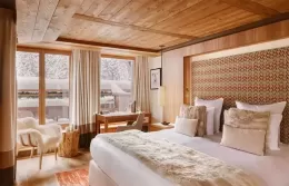 Cozy Junior Suite with a large bed, fur armchair, and panoramic windows.
