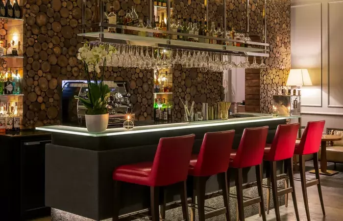 Lounge bar with red bar stools and a log-stack wall, Hotel Mont-Blanc Chamonix