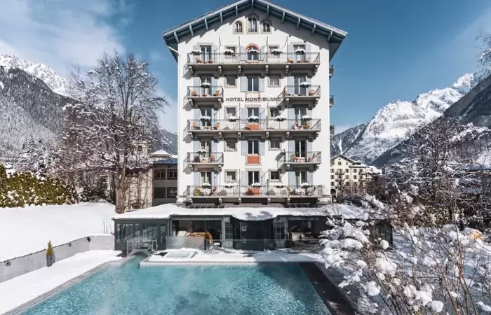 White facade and balconies of Hotel Mont-Blanc Chamonix above the outdoor pool in winter