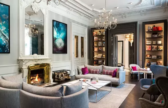 Lounge with marble fireplace, grey sofas and bookshelves at Hotel Mont-Blanc Chamonix
