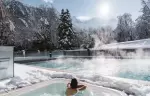 Steaming outdoor pool and hot tub among snowy fir trees at Hotel Mont-Blanc Chamonix