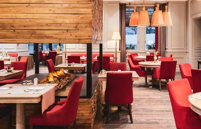Le Matafan restaurant with red armchairs around a central open fire, Hotel Mont-Blanc Chamonix