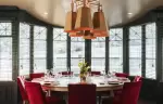 Round table laid for dinner in a bay-windowed dining room, Hotel Mont-Blanc Chamonix