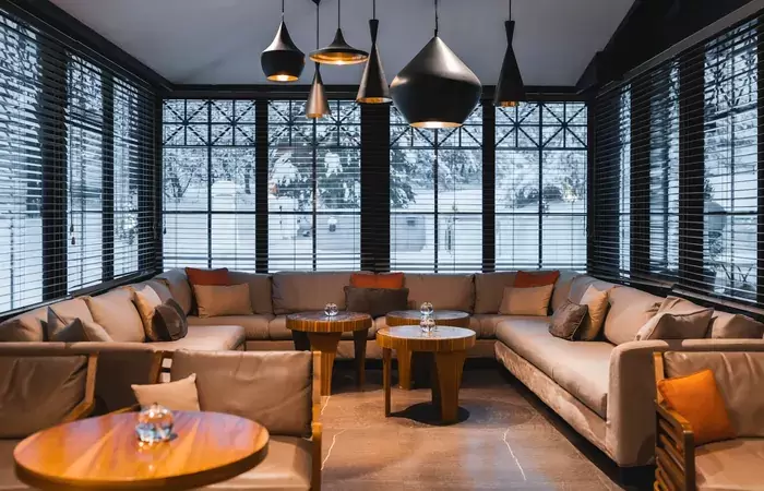 Corner sofas under pendant lamps beside snowy windows at Le Matafan, Hotel Mont-Blanc Chamonix