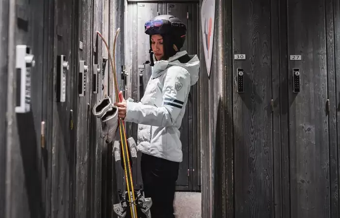 Woman with skis at a private wooden locker in the ski room, Hotel Mont-Blanc Chamonix