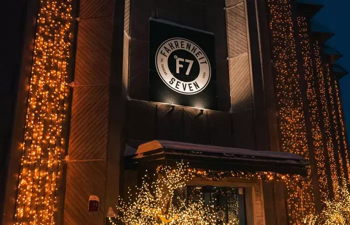 Illuminated entrance of Fahrenheit Seven Val Thorens hotel with the F7 logo at night