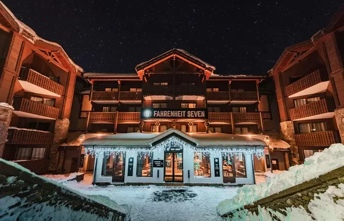 Illuminated facade of Fahrenheit Seven Courchevel hotel on a winter night
