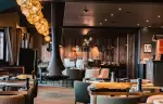 La Cheminee restaurant interior with central fireplace at Fahrenheit Seven Courchevel