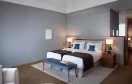A Deluxe Room with twin beds and a blue bench at Chenot Palace Weggis, Lake Lucerne