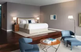 A Junior Suite bed on a wooden platform with blue armchairs, Chenot Palace Weggis