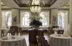 The dining room with a chandelier and white linen at Chenot Palace Weggis, Weggis