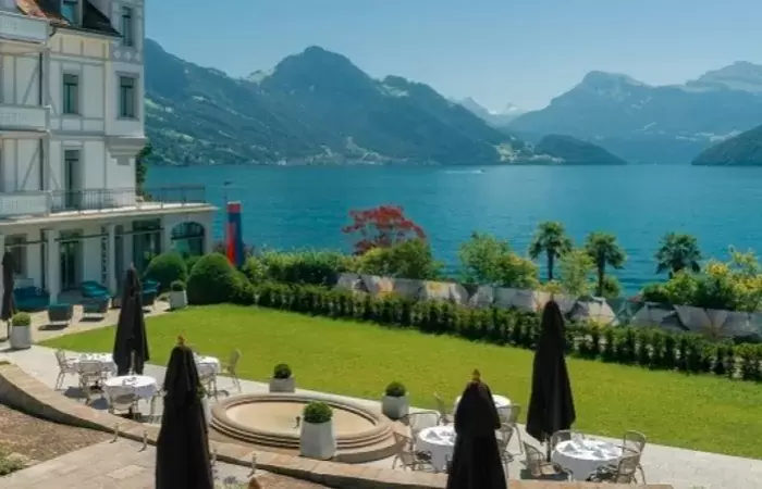 Terrace tables and parasols on the lawn facing the lake, Chenot Palace Weggis, Weggis