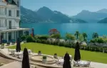 Terrace tables and parasols on the lawn facing the lake, Chenot Palace Weggis, Weggis