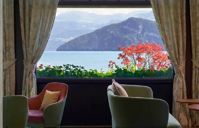 Armchairs at a window framing the lake and mountains, Chenot Palace Weggis, Weggis