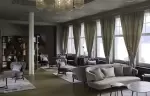 A lounge with sofas, glass chandeliers and tall windows at Chenot Palace Weggis