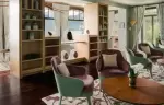 The tea lounge with green armchairs and open shelving at Chenot Palace Weggis