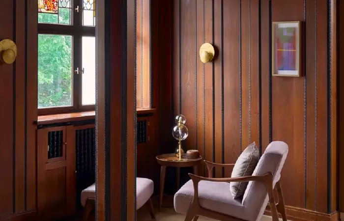 A wood-panelled corner with an armchair and stained glass, Chenot Palace Weggis