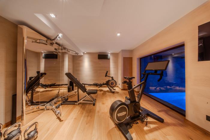 Modern fitness room with a view of the pool at Chalet Orso in Val d-Isere.