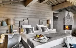 Prestige Suite bedroom with a corner fireplace under a wooden ceiling, Lys Martagon, Courchevel 1850