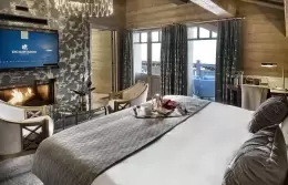 Deluxe Room 3 bedroom with a fireplace set below the television, Lys Martagon, Courchevel 1850