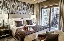 Deluxe Room 1 bedroom with glass doors onto a stone-walled terrace, Lys Martagon, Courchevel 1850