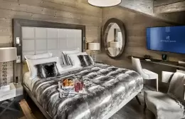 Deluxe Room 2 bed with a padded headboard and a grey throw, Lys Martagon, Courchevel 1850