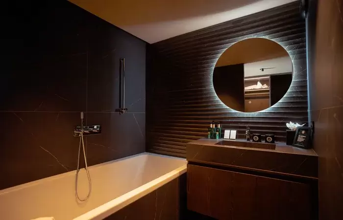 Bathroom with bathtub and backlit round mirror at Fahrenheit Seven Les Menuires