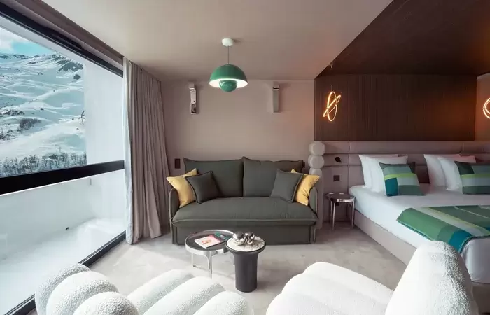 Room with sofa and bay window overlooking the slopes at Fahrenheit Seven Les Menuires