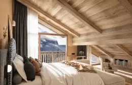 Deluxe Junior Suite with a fireplace and a bed under a sloping timber ceiling at Barma, La Tania
