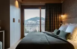 Bedroom with a dark throw and a balcony door onto the mountains, Duplex Signature Apartment, Barma Residence