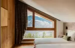 Bedroom under a sloping ceiling with a wide window onto the forest, Barma Residence La Tania