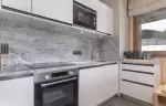 Fitted kitchen with stone-effect splashback, oven and microwave at Barma Residence, Courchevel La Tania