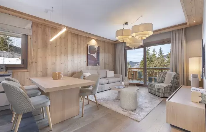 Living and dining area opening onto a wooden balcony and fir trees at Barma Residence, La Tania