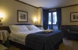 A Classic Room with a tartan bedspread and an armchair, Hotel Hermitage, Breuil-Cervinia