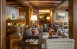 The wood-panelled lounge with a fireplace at Hotel Hermitage, Breuil-Cervinia
