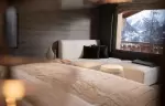 A bedroom with a sofa under a window facing the mountains at No. 14 Verbier