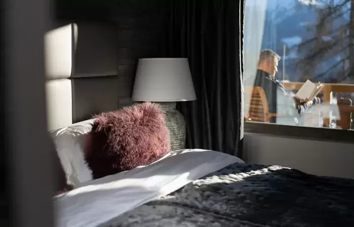 A bedroom with a fur cushion and a window onto the balcony at No. 14 Verbier