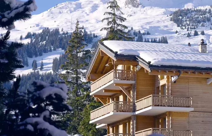 The chalet seen between snow-covered fir trees at No. 14 Verbier