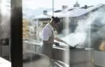 A chef cooking at the outdoor grill behind a glass wall at No. 14 Verbier